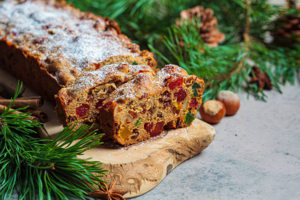 Traditional Christmas fruit cake on a wooden board in a festive decoration.