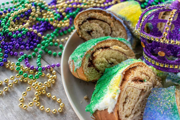 Sliced Mardi Gras king cake surrounded by colorful beads